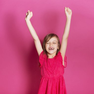 Küçük 8 yaşında kız elleri pembe tarafsız arka plan üzerinde bazı duygusal jest yapmak. O uzun esmer saç ve giyim kırmızı yazlık elbise vardır. Yüzünde komik ifade