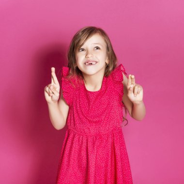 Küçük 8 yaşında kız elleri pembe tarafsız arka plan üzerinde bazı duygusal jest yapmak. O uzun esmer saç ve giyim kırmızı yazlık elbise vardır. Yüzünde komik ifade