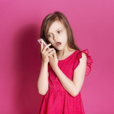 Küçük 8 yaşında kız elleri pembe tarafsız arka plan üzerinde bazı duygusal jest yapmak. O uzun esmer saç ve giyim kırmızı yazlık elbise vardır. Yüzünde komik ifade