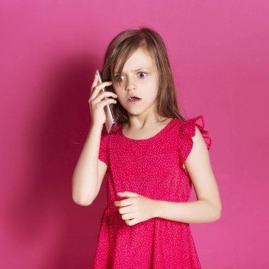 Küçük 8 yaşında kız elleri pembe tarafsız arka plan üzerinde bazı duygusal jest yapmak. O uzun esmer saç ve giyim kırmızı yazlık elbise vardır. Yüzünde komik ifade