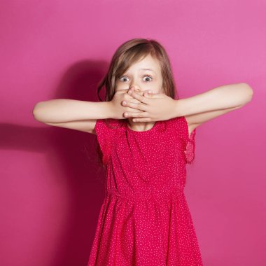 Küçük 8 yaşında kız elleri pembe tarafsız arka plan üzerinde bazı duygusal jest yapmak. O uzun esmer saç ve giyim kırmızı yazlık elbise vardır. Yüzünde komik ifade