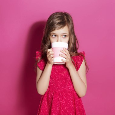 Küçük 8 yaşında kız elleri pembe tarafsız arka plan üzerinde bazı duygusal jest yapmak. O uzun esmer saç ve giyim kırmızı yazlık elbise vardır. Yüzünde komik ifade