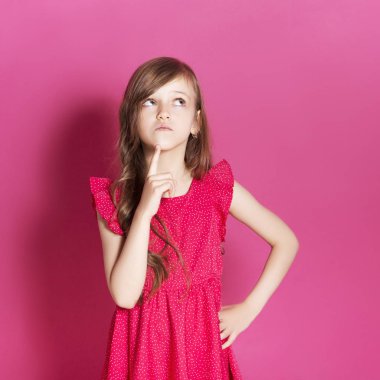 Küçük 8 yaşında kız elleri pembe tarafsız arka plan üzerinde bazı duygusal jest yapmak. O uzun esmer saç ve giyim kırmızı yazlık elbise vardır. Yüzünde komik ifade