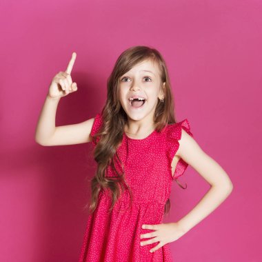 Küçük 8 yaşında kız elleri pembe tarafsız arka plan üzerinde bazı duygusal jest yapmak. O uzun esmer saç ve giyim kırmızı yazlık elbise vardır. Yüzünde komik ifade