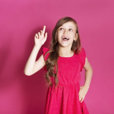 Küçük 8 yaşında kız elleri pembe tarafsız arka plan üzerinde bazı duygusal jest yapmak. O uzun esmer saç ve giyim kırmızı yazlık elbise vardır. Yüzünde komik ifade