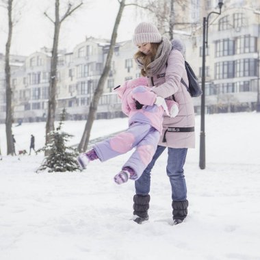 Anne-baba-kız oyun oynayıp kış karlı parkında eğlenen beyaz ve mutlu bir aile. Sevimli küçük kız oynuyor