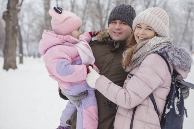 Anne-baba-kız oyun oynayıp kış karlı parkında eğlenen mutlu beyaz aile.