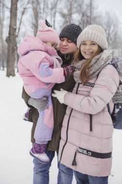 Anne-baba-kız oyun oynayıp kış karlı parkında eğlenen mutlu beyaz aile.