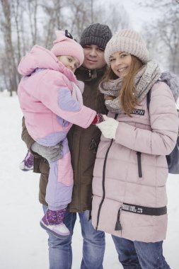 Anne-baba-kız oyun oynayıp kış karlı parkında eğlenen mutlu beyaz aile.