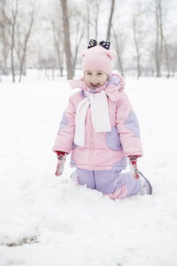 Anne-baba-kız oyun oynayıp kış karlı parkında eğlenen beyaz ve mutlu bir aile. Sevimli küçük kız oynuyor