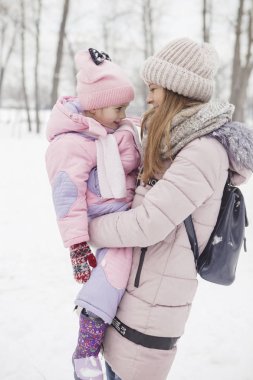 Anne-baba-kız oyun oynayıp kış karlı parkında eğlenen mutlu beyaz aile.