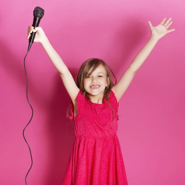 Küçük 8 yaşında kız elleri pembe tarafsız arka plan üzerinde bazı duygusal jest yapmak. O uzun esmer saç ve giyim kırmızı yazlık elbise vardır. Yüzünde komik ifade