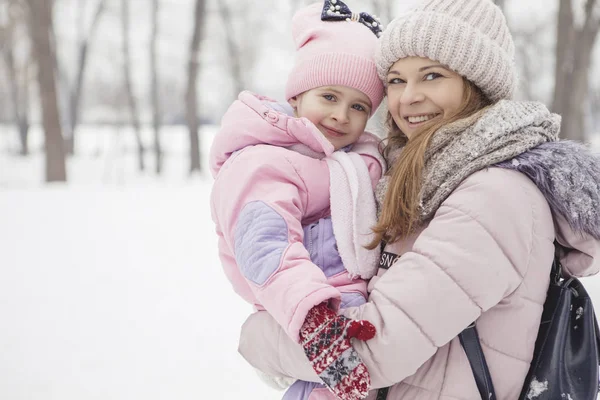 Anne-baba-kız oyun oynayıp kış karlı parkında eğlenen mutlu beyaz aile.