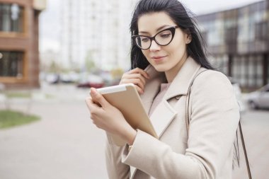 Açık havada ceket, soğuk hava bir sokakta yürüyen kadın. O tablet aygıtı için bir iş (iş), serbest çalışan olarak office dışında bir proje üzerinde kullanın. Alan, alan için metin kopyalama