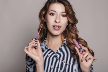 Esmer kadın kendini bir akşam tarih veya düğün için hazırlık için makyaj uygulanması. Nötr arka plan. Kusursuz doğal cilt