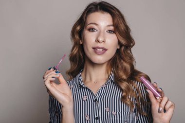 Esmer kadın kendini bir akşam tarih veya düğün için hazırlık için makyaj uygulanması. Nötr arka plan. Kusursuz doğal cilt