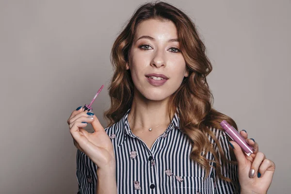 Esmer kadın kendini bir akşam tarih veya düğün için hazırlık için makyaj uygulanması. Nötr arka plan. Kusursuz doğal cilt