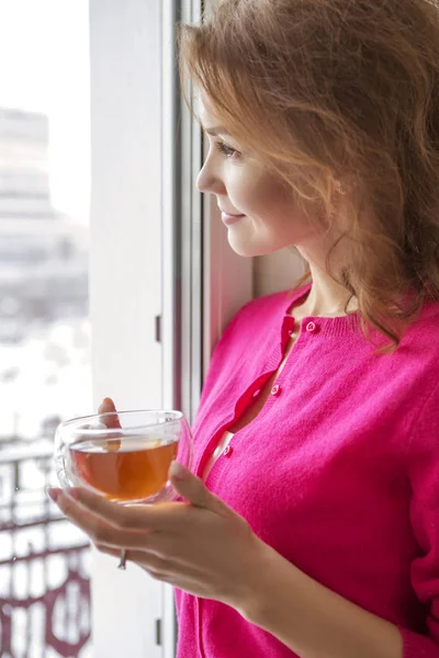 マグカップからお茶を飲んで 家の彼女の豪華なインテリアにカジュアルな服立って女性を美しい女性 彼女の顔に明るい笑顔 — ストック写真