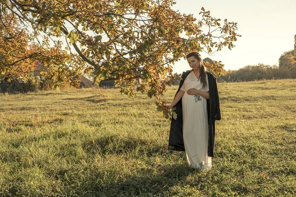 可爱的怀孕的白种人妇女在秋天冷的公园在步行的礼服和外套 — 图库照片