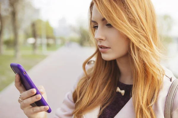 红头发性感加大小的女人走在公园 天气寒冷 她穿着皮夹克 她在手机上工作 在社交媒体上发短信 — 图库照片