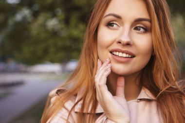 Kızıl saçlı seksi artı bir parkta yürüyen boyutu kadın. Soğuk havada deri ceket giyiyor. Duygusal portre