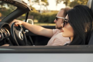 Yaz günü bir tatil araba gezisi erkek ve kadın Muhteşem seksi copule. Lüks gri spor araba. Seksi uygun esmer kadın ve rahat kıyafetli adam. Günbatımı.