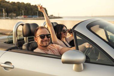 Yaz günü bir tatil araba gezisi erkek ve kadın Muhteşem seksi copule. Lüks gri spor araba. Seksi uygun esmer kadın ve rahat kıyafetli adam. Günbatımı.