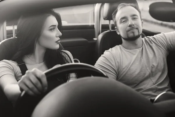 Gorgeous sexy copule of man and woman on a vacation car trip in summer day. Luxury grey sport car. Sexy fit brunette woman and man in casual outfit. Sunset.