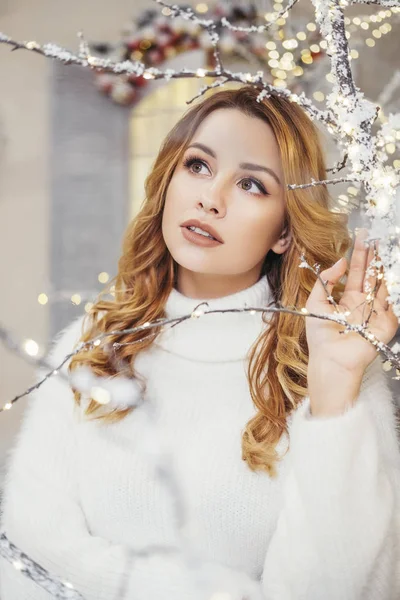 花輪やクリスマスの飾りで覆われた家の近くにかわいいプラスサイズの女性 彼女は白い居心地の良いセーターを着ている テキスト用のスペース — ストック写真