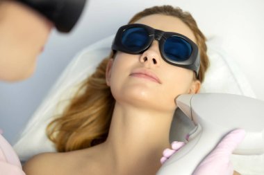 Kadın doktor güzellik uzmanı saç lazer Epilatör kullanarak bir kadın istemci vücuttan çıkarma. Onlar bir spa merkezi.