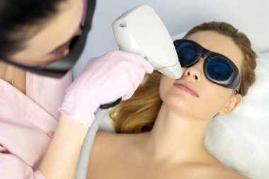 Kadın doktor güzellik uzmanı saç lazer Epilatör kullanarak bir kadın istemci vücuttan çıkarma. Onlar bir spa merkezi.