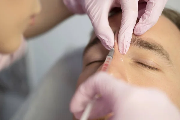 Closeup Of Beauty master Doing Injection In Young Male Patient Face. Man receiving Beauty Procedure Using Filler Injections. Cosmetology And Beauty Concept of facial Injection