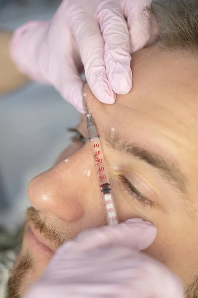 Closeup Of Beauty master Doing Injection In Young Male Patient Face. Man receiving Beauty Procedure Using Filler Injections. Cosmetology And Beauty Concept of facial Injection
