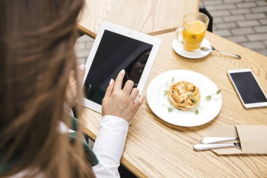 Bir yaz teras kafede bir freelancer olarak çalışan esmer iş kadın. Onun iş için çay ve kullanım araçları dizüstü ve tablet ve telefon gibi içiyor. Metin için yer. Üstten Üstten Görünüm.