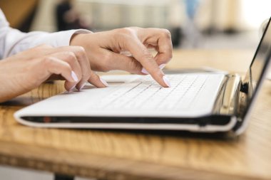 Kafeterya masada oturan bir dizüstü bilgisayar klavye sıcak güneşli bir gün açık havada, içinde yazarak kadın. Metin için yer.