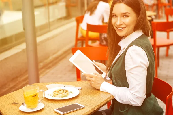 ブルネットのビジネスの女性は 夏のテラスでカフェからフリーランスとして働きます 彼女は彼女の仕事のラップトップとタブレットと電話として茶使いのガジェットを飲みます テキストのためのスペース — ストック写真