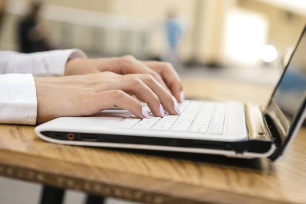 Woman typing on a laptop keyboard in a warm sunny day outdoors, sitting at the cafe table. Space for text.