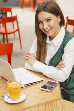 Bir yaz teras kafede bir freelancer olarak çalışan esmer iş kadın. Onun iş için çay ve kullanım araçları dizüstü ve tablet ve telefon gibi içiyor. Metin için yer.