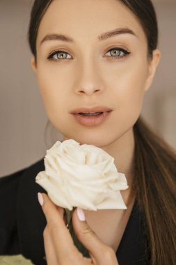 Sexy esmer beyaz kadın elbise ve ceket evde uygun. Oldukça kusursuz yüz. O çiçek tutan.