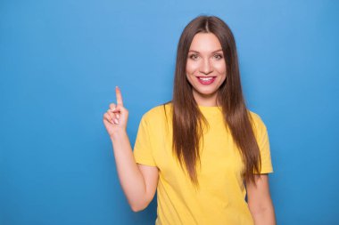 Uzun saçlı sevimli esmer kadın üzerinde sarı t-shirt poz