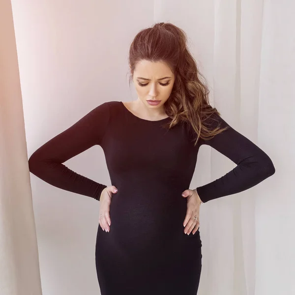 Linda mulher grávida morena em casa em vestido preto — Fotografia de Stock