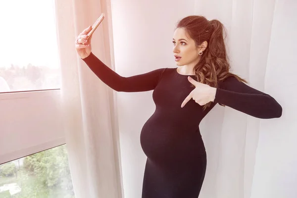 Preciosa morena embarazada con vientre grande en vestido negro s —  Fotos de Stock