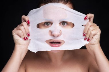 Güzel genç Avrupalı kadın yüzüne kilden maske takıyor. Beau.