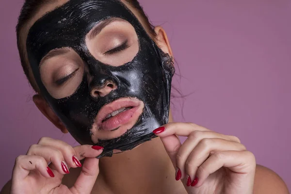 Mooie jonge Europese vrouw brengen klei masker op haar gezicht. beau — Stockfoto