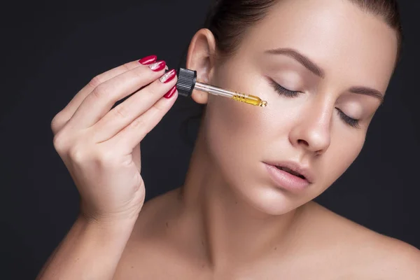 Brunette caucasian woman apply hyaluronic acid from a bottle usi — Stock Photo, Image