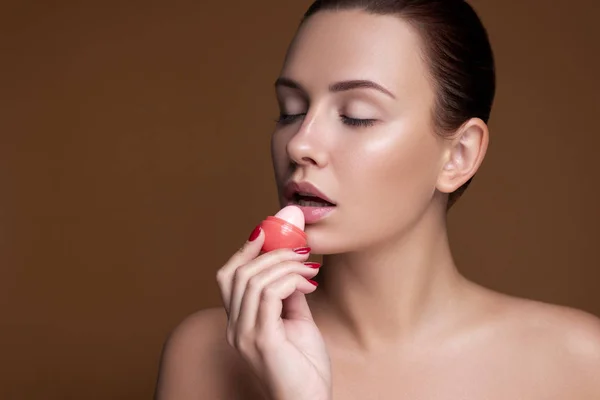 Brünette europäerin auftragen lippenstift auf ihre lippen auf rosa neutral — Stockfoto