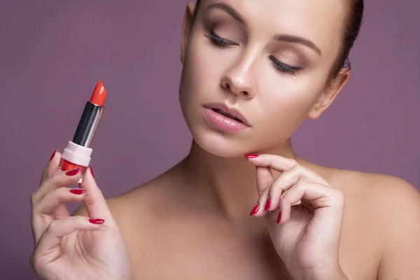 Brünette europäerin auftragen lippenstift auf ihre lippen auf rosa neutral — Stockfoto