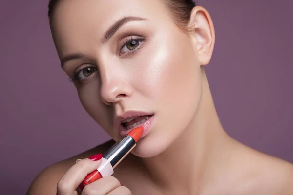 Brünette europäerin auftragen lippenstift auf ihre lippen auf rosa neutral — Stockfoto