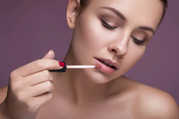 Brünette europäerin auftragen lippenstift auf ihre lippen auf rosa neutral — Stockfoto