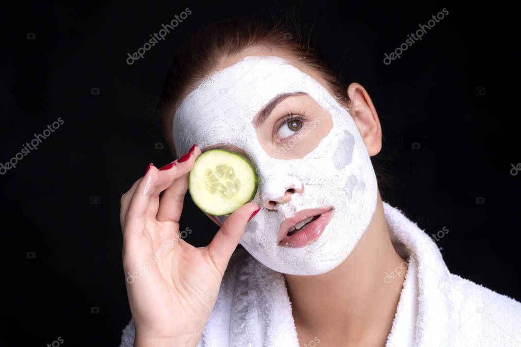 Beautiful young european woman apply clay mask on her face with 